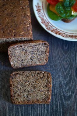 Zımba gibi bir yiyecek, bir somun ekmek, bir tabak sebzenin yanındaki ahşap bir masaya yerleştirilir. Dikdörtgen tabakta renkli ve sağlıklı bir tabak var.