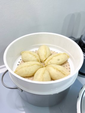 İçinde sebzeler, etler ve tahıllar gibi lezzetli bir yemek için pişirilmeye ve servis edilmeye hazır yiyeceklerle dolu bir buharlı tencere.