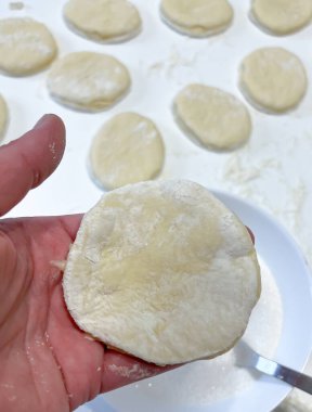 Bir insan, yemek pişirmek için kullanılan bir malzemeyi manipüle ediyor. Ellerindeki hamur parçasını yemek mutfağındaki bir tariften bir yemek hazırlamak için şekillendiriyor.