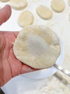 Bir insan elinde bir parça hamur tutuyor ve lezzetli bir yemek yapmaya hazırlanıyor. Bu temel bileşen birçok pişirilmiş malın temelidir ve çeşitli yemek tariflerinde kritiktir.