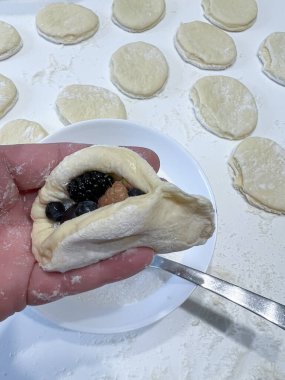 Bir insan bir parça yaban mersinli hamuru tutuyor, atıştırmalık olarak hazırlanmış. Bu güzel fırın lezzetli bir ikram olabilir.