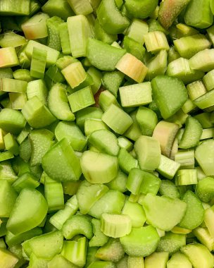 Genellikle tariflerde malzeme olarak kullanılan bir bitki olan doğranmış ravent yığını bir masanın üzerinde duruyor. Bu sebze bazı mutfakların temel gıdasıdır ve turta tadı ile ünlüdür.