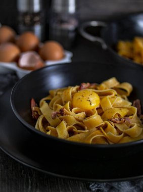 Masada yumurta ve pastırmayla servis edilen, al dente pişirilmiş lazanya tabağı. İtalyan mutfağının klasik malzemelerini birleştiren lezzetli bir tarif.