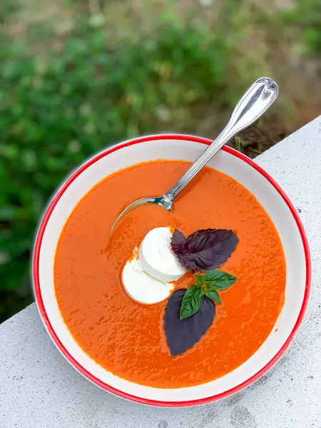 Yanında kaşıkla süslenmiş havuç ve kırmızı mercimek çorbası. Rahatlatıcı ve besleyici bir yemek için mükemmel.