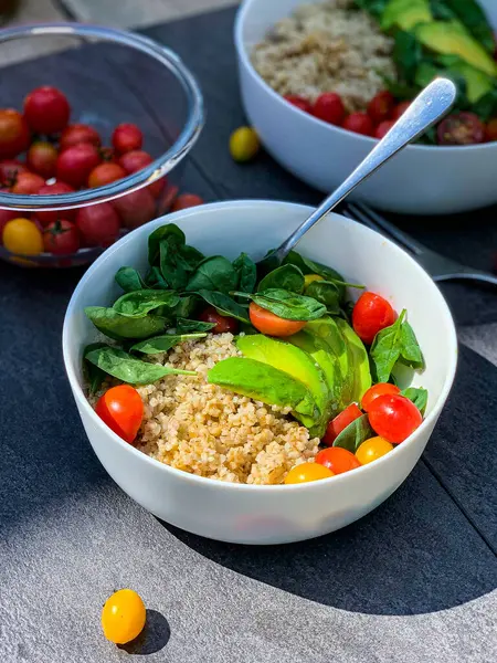 Lezzetli bir kâse avokado, domates, ıspanak ve pirinçle kaplı bir masa. Zımba ve doğal malzemelerin mükemmel bir kombinasyonu.