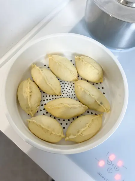 Bir tabak yemek ocakta dinleniyor, muhtemelen pişirilmeye hazır. Rahatlatıcı bir yemek tarifi ya da kızartılmayı bekleyen bir yemek tabağı olabilir.