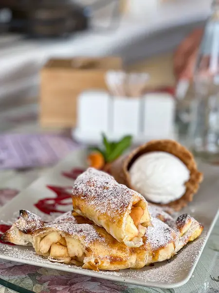 Masanın üzerinde bir tabak elmalı turta ve dondurma. Lezzetli bir yemek ve tatlı karışımı sunuyor.