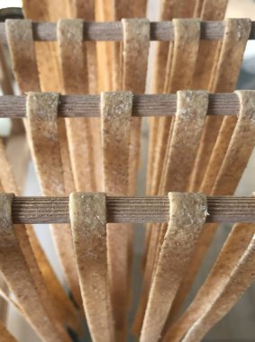 Doğal ahşap kaplamalı bir yığın ahşap çubuk bir masanın üzerine dizilir. Bu tablo, bir çiti ya da hasır tasarımını andıran güzel bir desen sergiliyor.