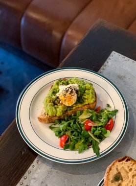 Canlı bir tabak avokado tostu ve mükemmel pişmiş bir yumurta. Yanında da taze, renkli bir salata.