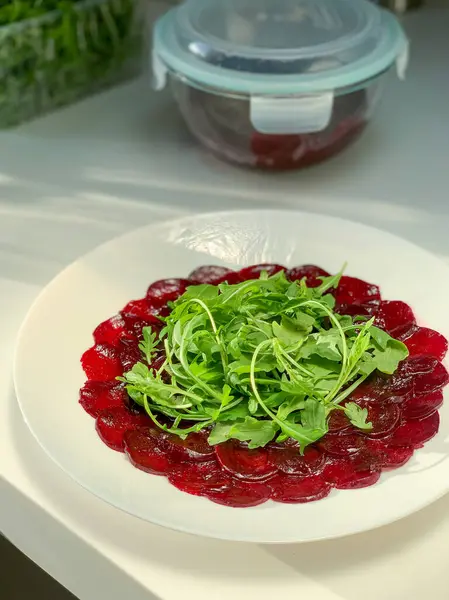 Bu canlı ve renkli pancar carpaccio, sanatsal olarak taze roka ile kaplıdır, sağlıklı beslenmek için mükemmeldir.
