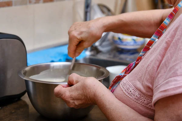 Close-up of the hands of an elderly woman with arthritis while cooking at home