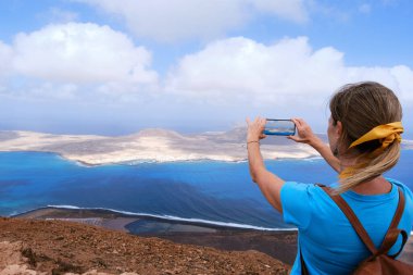 Kadın akıllı telefonuyla La Graciosa Adası 'nın fotoğrafını çekiyor. Lanzarote, Kanarya Adaları.