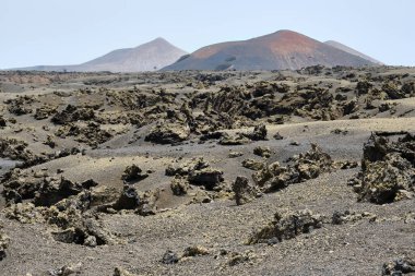 Volkanik manzara. Volkanik taşlar ve arka planda volkanlar olan mineraller. Lanzarote.