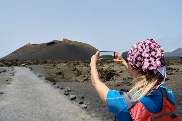 妇女徒步旅行者用她的手机拍摄埃尔奎沃火山 兰萨罗特加那利群岛 — 图库照片