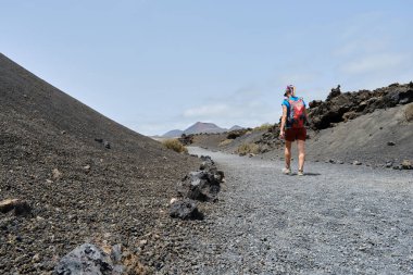 Lanzarote 'deki volkanlar arasında yürüyen bir turist. Kanarya Adaları