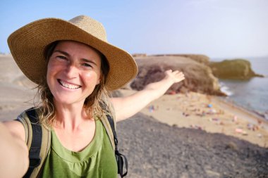 Kadın turist, arka planda, Kanarya Adaları 'nda ünlü Papagayo plajıyla selfie çekiyor ve selfie çekiyor..