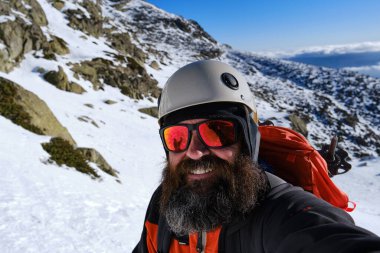 Dağcı yürüyüş sırasında karlı arazide selfie çekiyor.