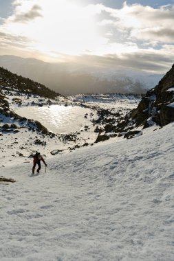 Tanınmayan yürüyüşçü, karlı dağ yamacında yürüyor.