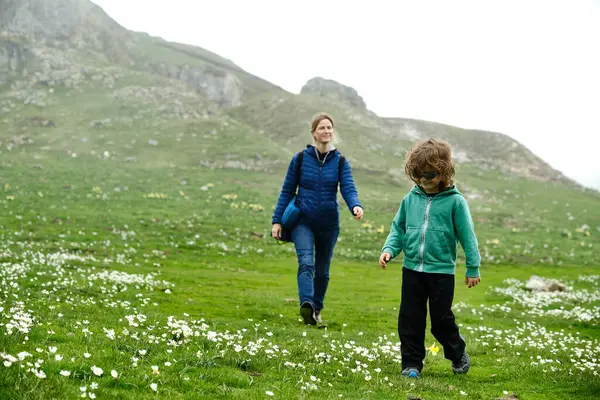 Child with his mother walking through a field with flowers