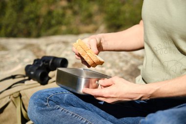 Oturan kadın paslanmaz çelikten bir yemek kutusundan sandviç çıkarıyor. Plastik olmayan kavram