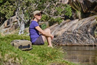 Nehir kenarında dinlenen bir kadın yürüyüşçü.