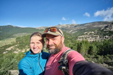 Dağda yürüyüş yaparken selfie çeken bir çift.