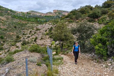 Arka planda Alquezar köyüyle yürüyüş yapan bir kadın..