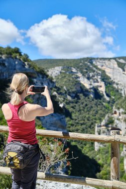 Bir kadın yürüyüşçünün, bir bakış açısıyla fotoğraf çekmesine arka bakış..
