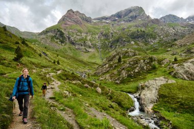 Anne ve oğul bulutlu bir günde nehir kenarında bir patika boyunca yürüyorlar..