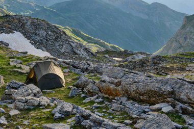 Kayalık bir dağın eteklerine kurulmuş yeşil çadır ana kampın keyfini çıkarıyor. Aragonlu Pireneler