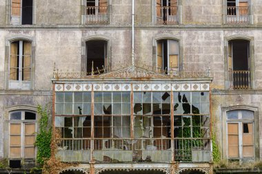 Kırık camları olan eski bir binanın ön cephesi.