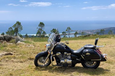 Okyanus manzaralı güzel bir arka planda klasik siyah motosiklet, dağdan manzara.