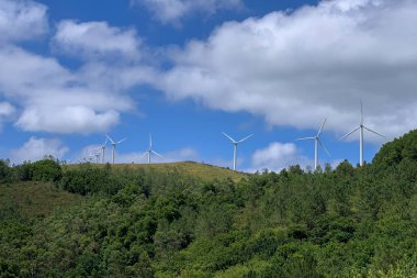 Güneşli bir günde bulutlu mavi gökyüzüne karşı rüzgar enerjisi santralleri