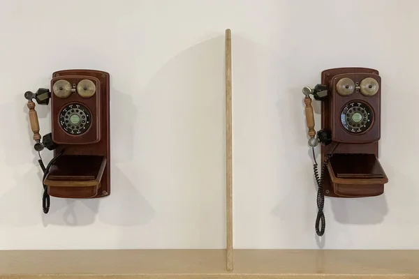 two vintage wooden telephones hanging on a white wall