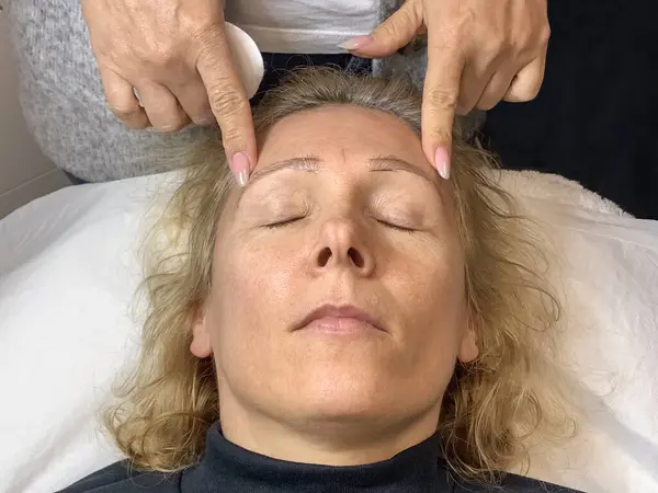 woman\'s face in a beauty salon during eyebrow tattooing, close-up