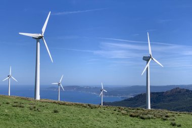 Güneşli bir günde bulutlu mavi gökyüzüne karşı rüzgar enerjisi santralleri