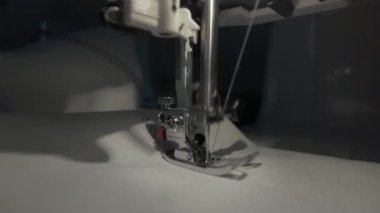 Dikiş makinesi çalışıyor, iğne dikişler beyaz kumaş, yakın çekim, yavaş çekim
