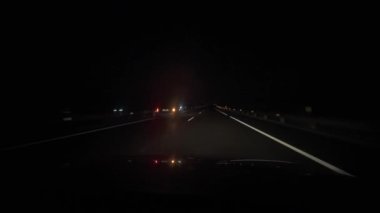Sürücü, arabasının konsolunda telefonuyla navigasyon kullanıyor, gece yolda araba kullanıyor.