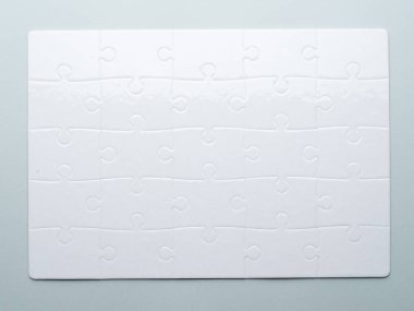 Yapbozun üst görüntüsü. Gri arkaplanda beyaz yapboz.