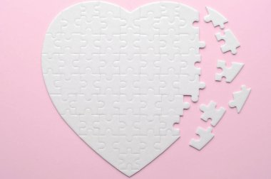 Beyaz kalp şeklinde yapboz. Gri bir arka planda. Birkaç parça kayıp ve yakınlarda. Aşkı, bağlantıyı ya da eksikliği simgeleyen, ilişkiler ve duygular için mükemmel.