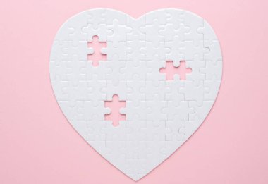 Beyaz kalp şeklinde yapboz. Gri bir arka planda. Birkaç parça kayıp ve yakınlarda. Aşkı, bağlantıyı ya da eksikliği simgeleyen, ilişkiler ve duygular için mükemmel.