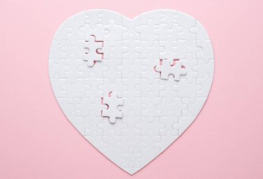 Beyaz kalp şeklinde yapboz. Gri bir arka planda. Birkaç parça kayıp ve yakınlarda. Aşkı, bağlantıyı ya da eksikliği simgeleyen, ilişkiler ve duygular için mükemmel.