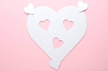 Beyaz kalp şeklinde yapboz. Gri bir arka planda. Birkaç parça kayıp ve yakınlarda. Aşkı, bağlantıyı ya da eksikliği simgeleyen, ilişkiler ve duygular için mükemmel.