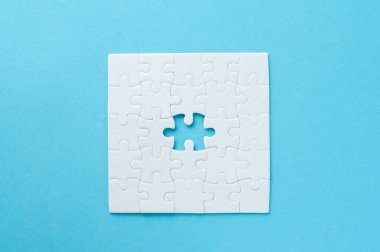 Beyaz yapboz, parlak mavi bir arka planda, bir parça eksik. Sorun çözme, takım çalışması, çözümler ya da eksik bağlantılar kavramı. Kopyalama alanı olan minimalist kompozisyon.