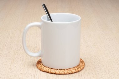 Kaşıklı kupa. Masadaki bardak altlığının üzerindeki boş 11ons beyaz bardak..