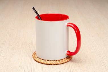 Kırmızı saplı ve iç kısımlı kupa. Çay kaşıklı kupa. Masadaki bardak altlığında iki tonluk bir bardak..