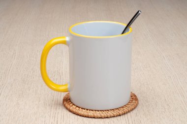 Sarı saplı ve iç kısımlı kupa. Çay kaşıklı kupa. Masadaki bardak altlığında iki tonluk bir bardak..