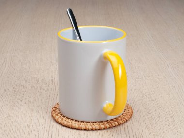 Sarı saplı ve iç kısımlı kupa. Çay kaşıklı kupa. Masadaki bardak altlığında iki tonluk bir bardak..