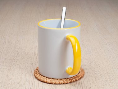 Sarı saplı ve iç kısımlı kupa. Çay kaşıklı kupa. Masadaki bardak altlığında iki tonluk bir bardak..