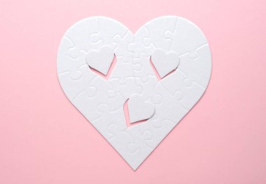 Beyaz kalp şeklinde yapboz. Gri bir arka planda. Birkaç parça kayıp ve yakınlarda. Aşkı, bağlantıyı ya da eksikliği simgeleyen, ilişkiler ve duygular için mükemmel.